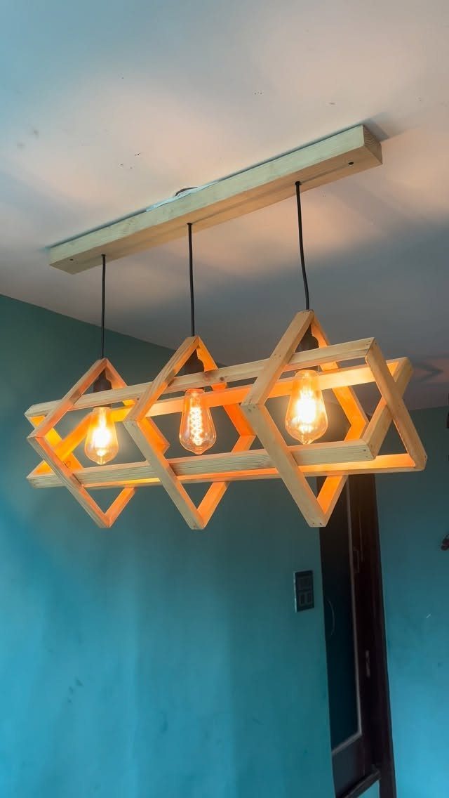 Art in Wood: 8 Ideas, From Knot Jewelry to Totem Pillars 1 Geometric wooden light fixture with three glowing bulbs hanging from a ceiling beam.
