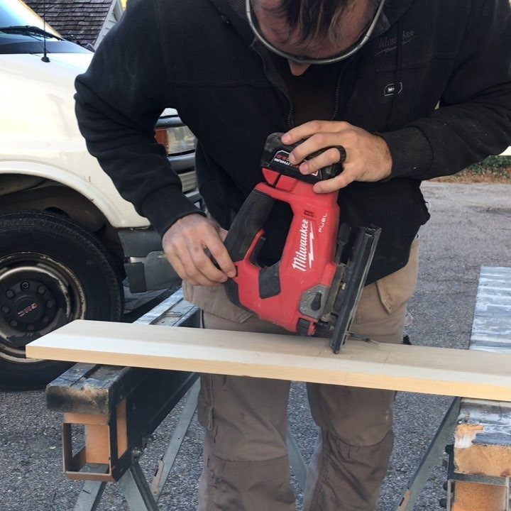13 Carpentry Tools and Equipment for Every Workshop 9 Person using a red circular saw to cut a wooden board on a workbench.