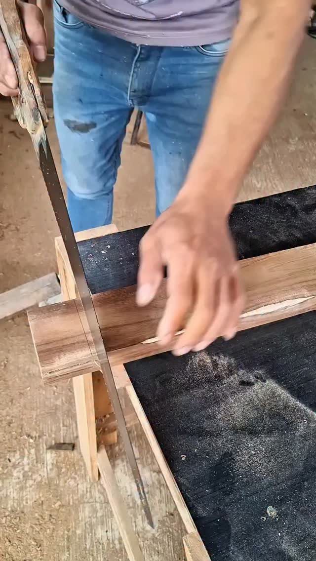 13 Carpentry Tools and Equipment for Every Workshop 11 Person using a hand saw to cut a wooden board on a workbench.