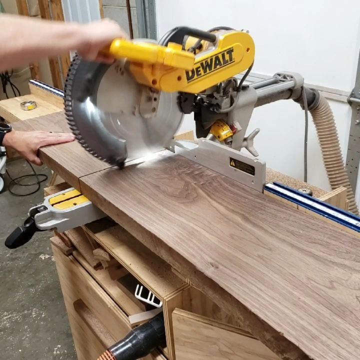 13 Carpentry Tools and Equipment for Every Workshop 4 Miter saw cutting through a thick piece of walnut wood on a workbench