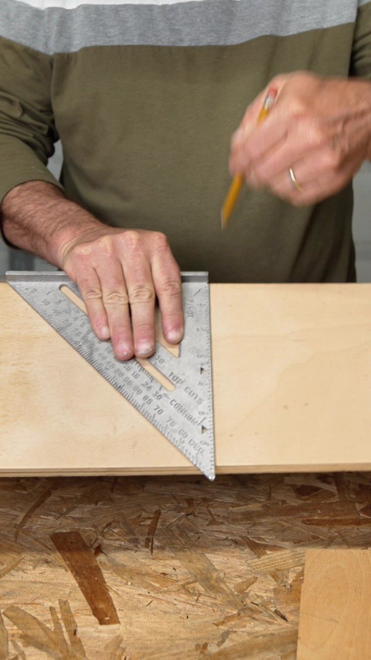 13 Carpentry Tools and Equipment for Every Workshop 6 Hands using a metal speed square and pencil to mark a wooden board.
