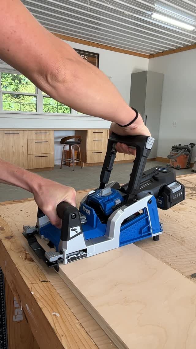 13 Carpentry Tools and Equipment for Every Workshop 12 Person using a blue power track saw to cut a wooden board on a workbench.
