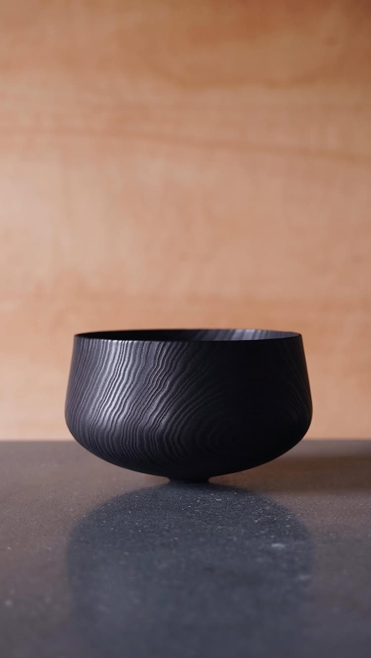 Charred wood bowl with deep textured grain on a dark grey surface.