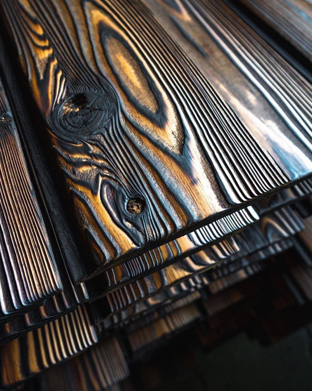 Stacked wooden planks with a black charred Shou Sugi Ban finish and golden grain.