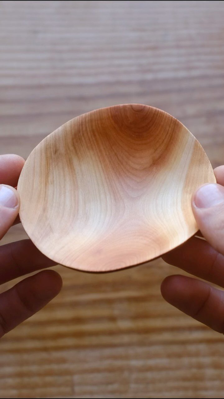 Cherry Wood Projects: 9 Ideas for Bowls, Boxes and More 1 Small hand-carved wooden bowl held by two hands against a wooden backdrop.