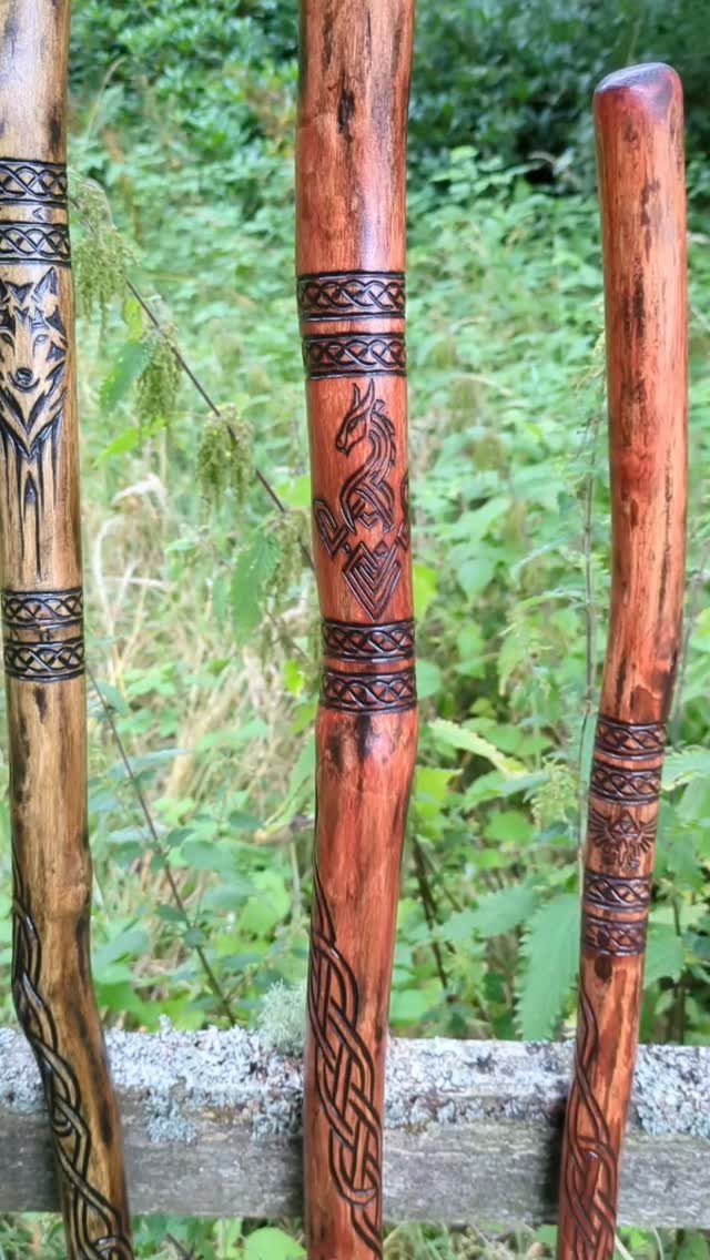 Cherry Wood Projects: 9 Ideas for Bowls, Boxes and More 6 Three carved wooden walking sticks with Celtic knots leaning against a rustic fence.