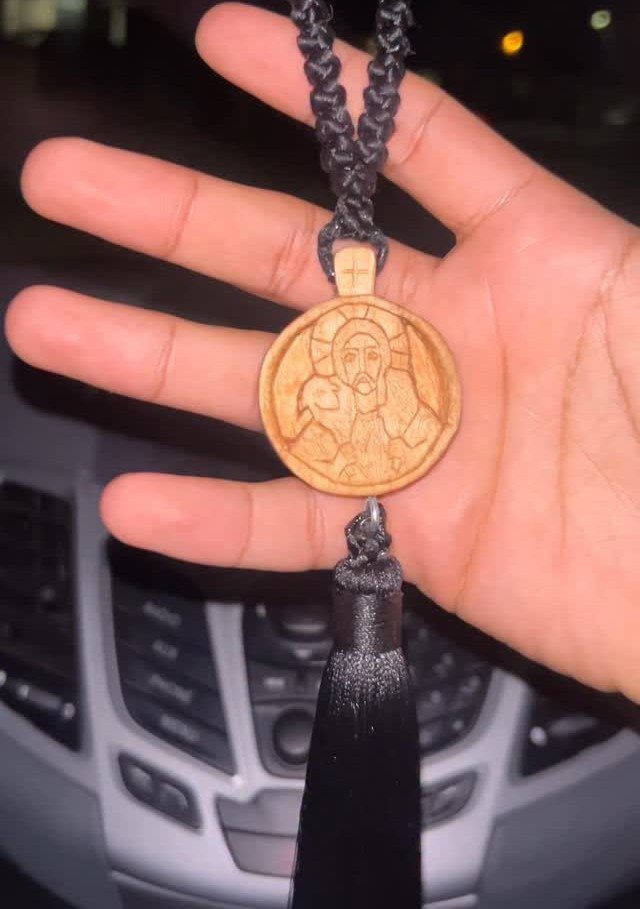 Christian Woodworking Projects: 9 Ideas for Home and Gifts 5 Wooden circular pendant with a carved image of Jesus held in a hand.