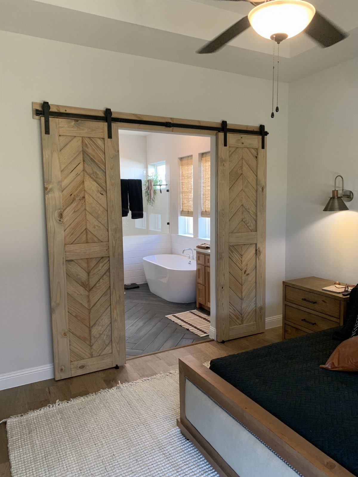 Creative Wood Designs: 8 Ideas for Furniture and Decor 1 Wooden sliding barn doors with chevron patterns opening into a modern white bathroom.