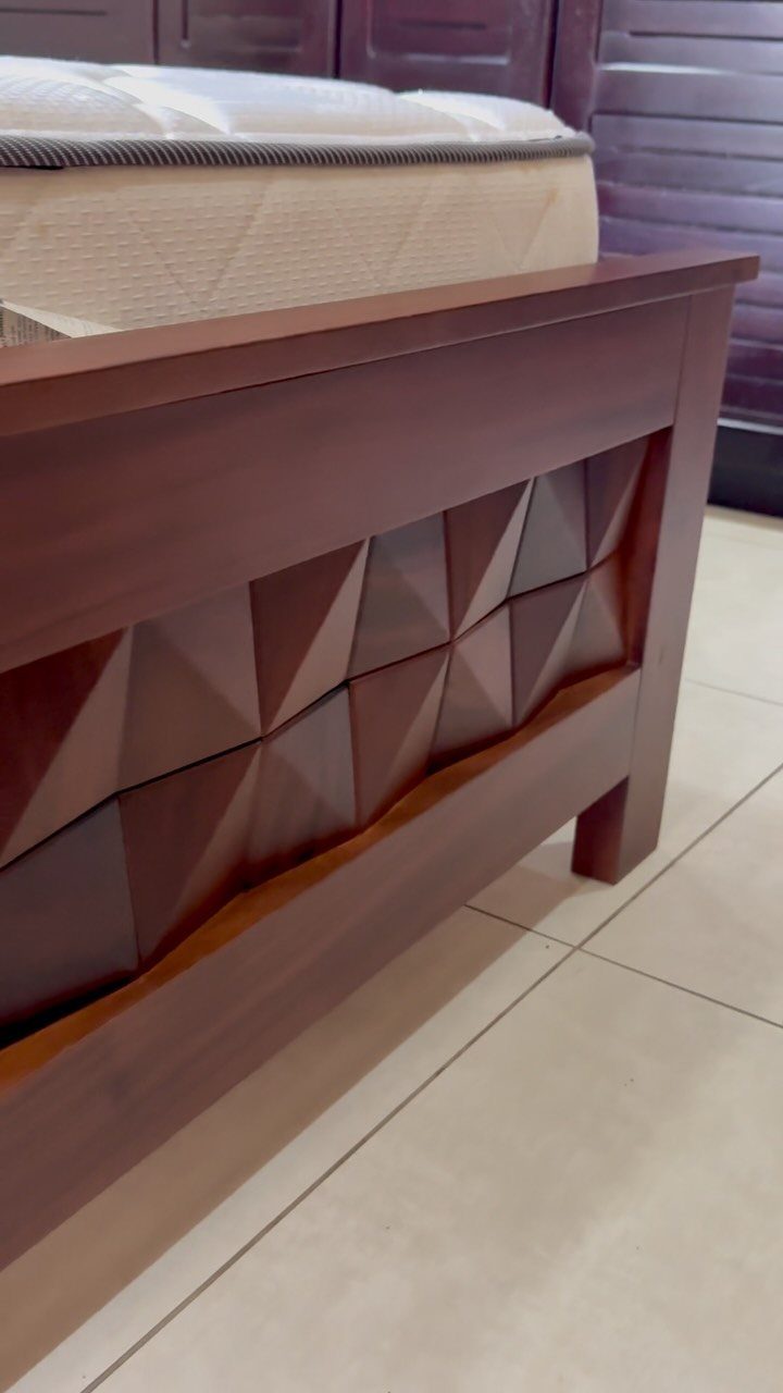 Dark brown wooden bed frame with geometric carved patterns and a white mattress