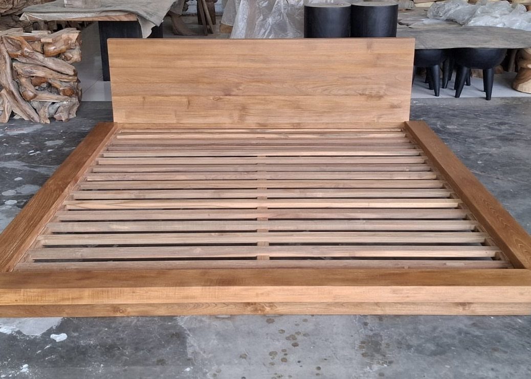 Wooden platform bed frame with a low headboard and slat support system.