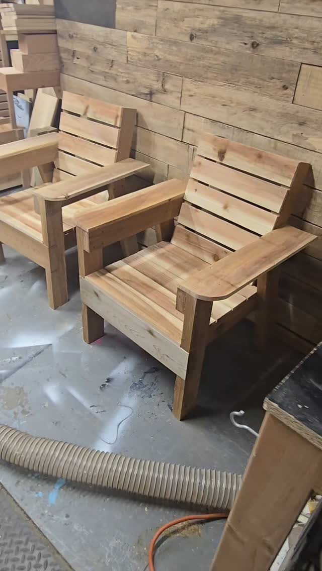 Two wooden lounge chairs with wide armrests in a woodworking shop setting