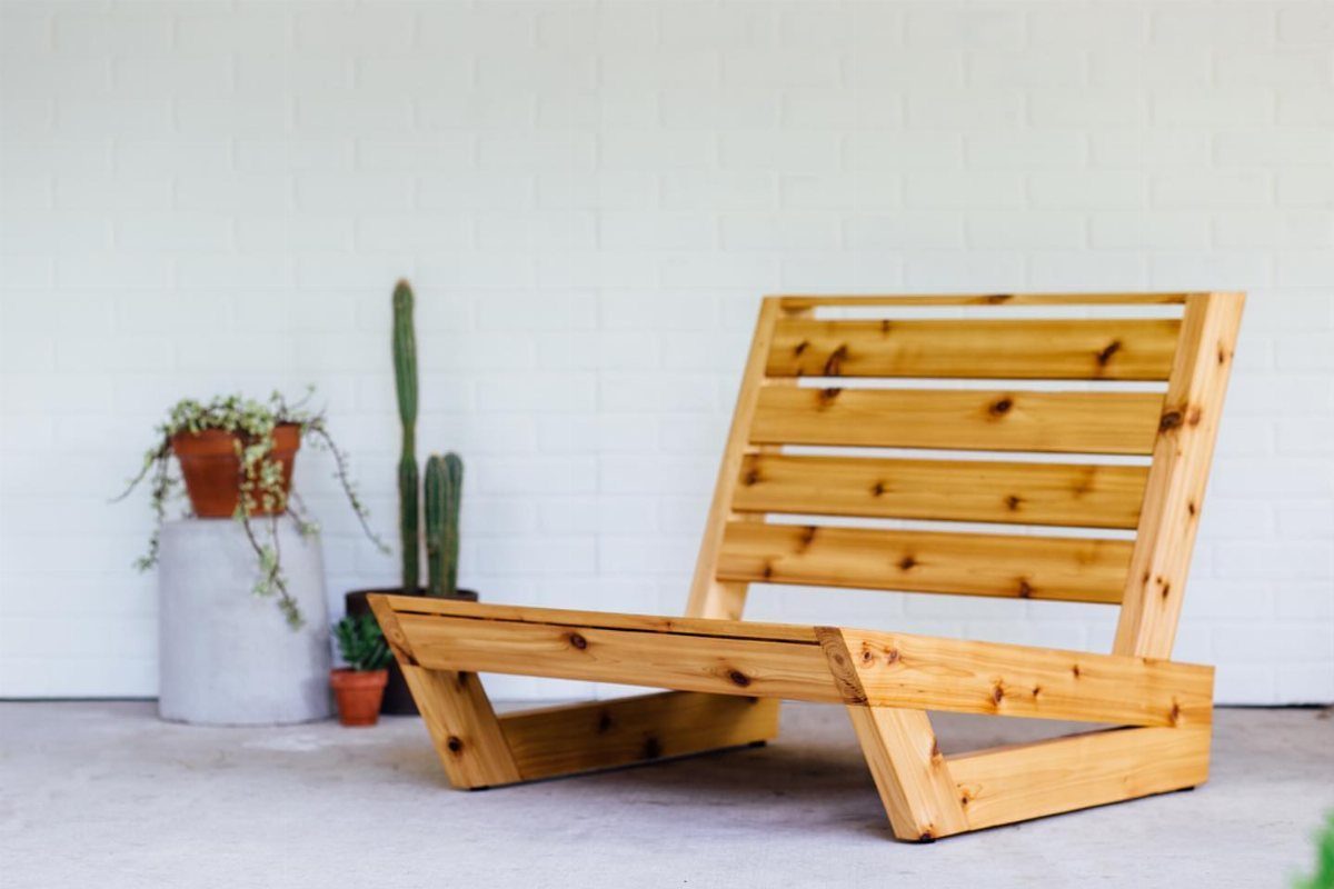 10 DIY Outdoor Chair Ideas for Patios, Porches and Decks 3 Wooden outdoor lounge chair with slatted back against a white brick wall.