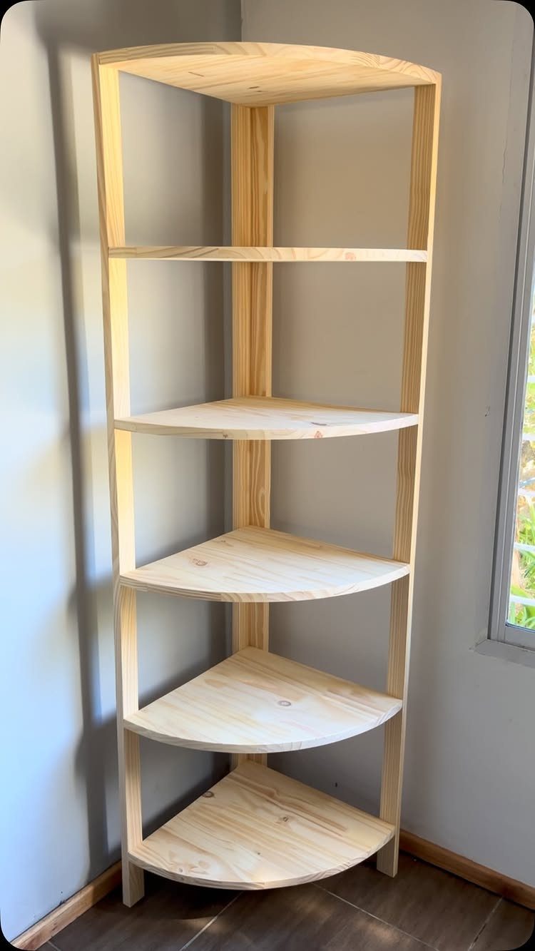 Light wooden corner shelving unit with five curved shelves against a grey wall.