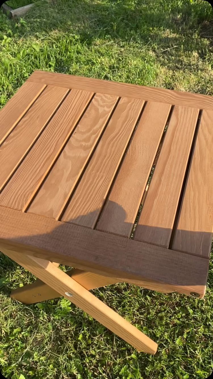 Small wooden folding table with a slatted top resting on green grass.