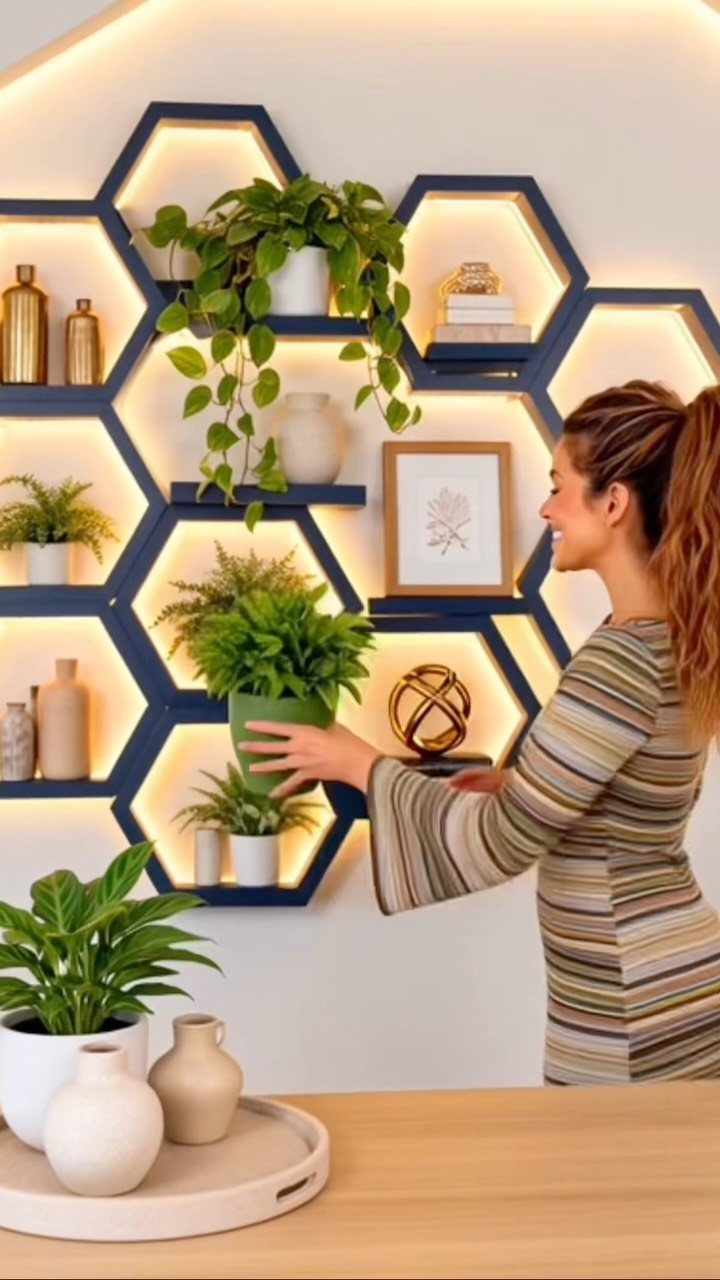 Navy blue hexagonal floating shelves on a wall with plants and warm backlighting.