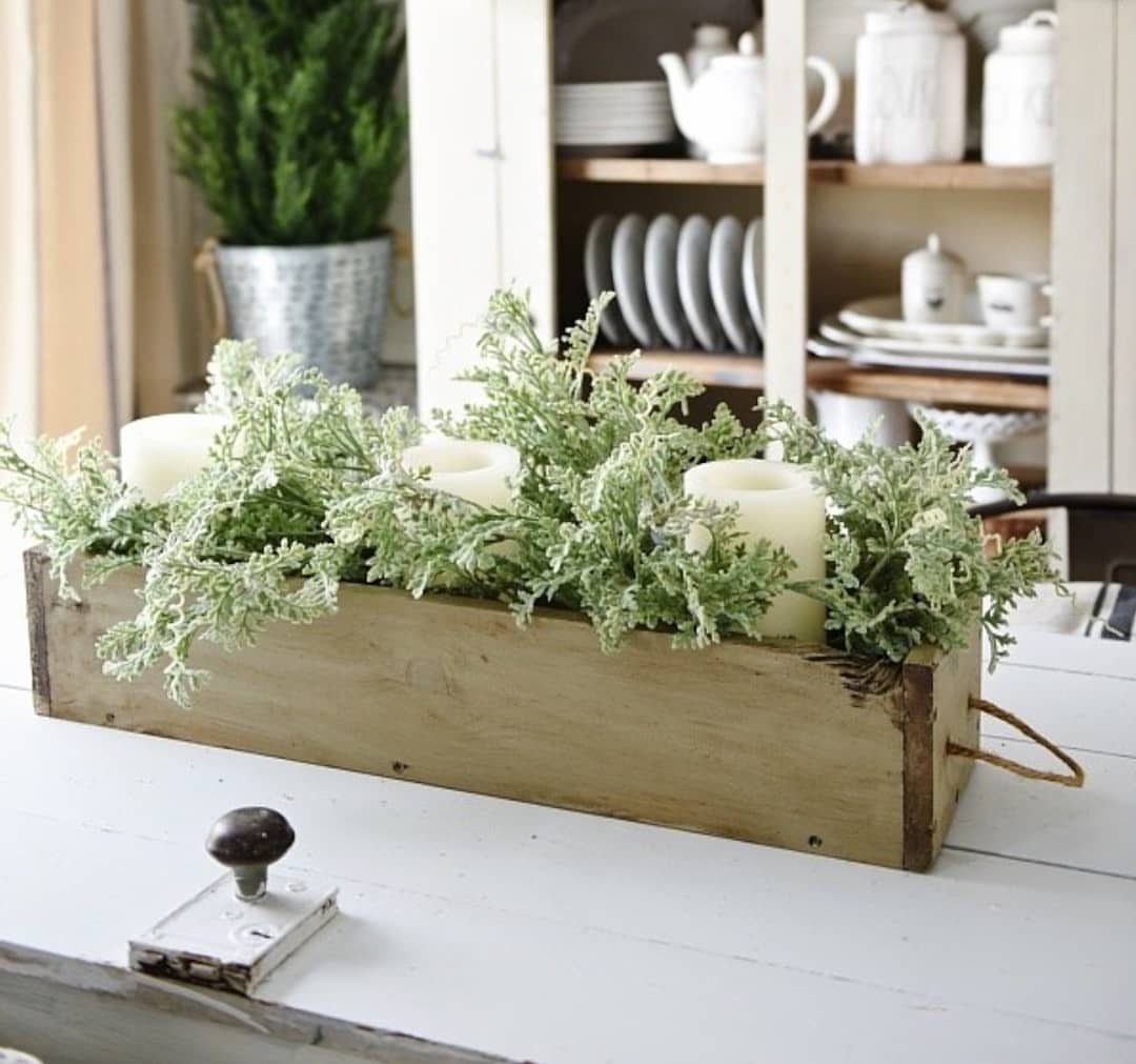 16 DIY Wooden Projects for Home, Garden, and Holiday Decor 8 Wooden planter box with green plants and white candles on a white table.