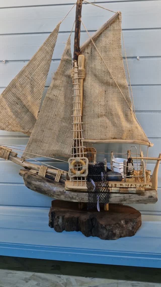 Driftwood model sailboat with burlap sails and twine rigging on a wooden base.
