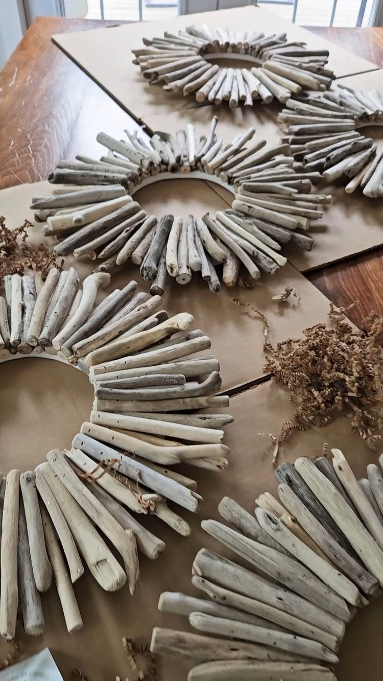 Circular driftwood wreaths made of weathered wood pieces resting on brown cardboard.
