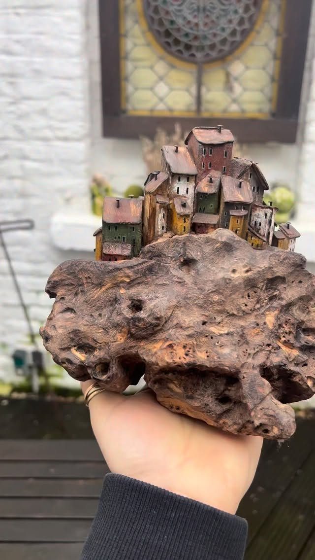 Miniature village of colorful houses carved into a piece of textured brown driftwood.