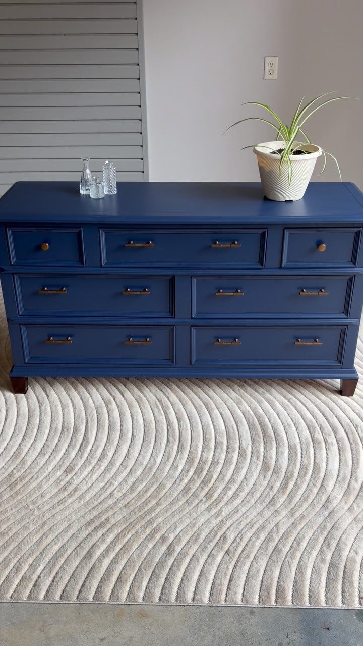 Navy blue painted dresser with gold handles on a white textured rug