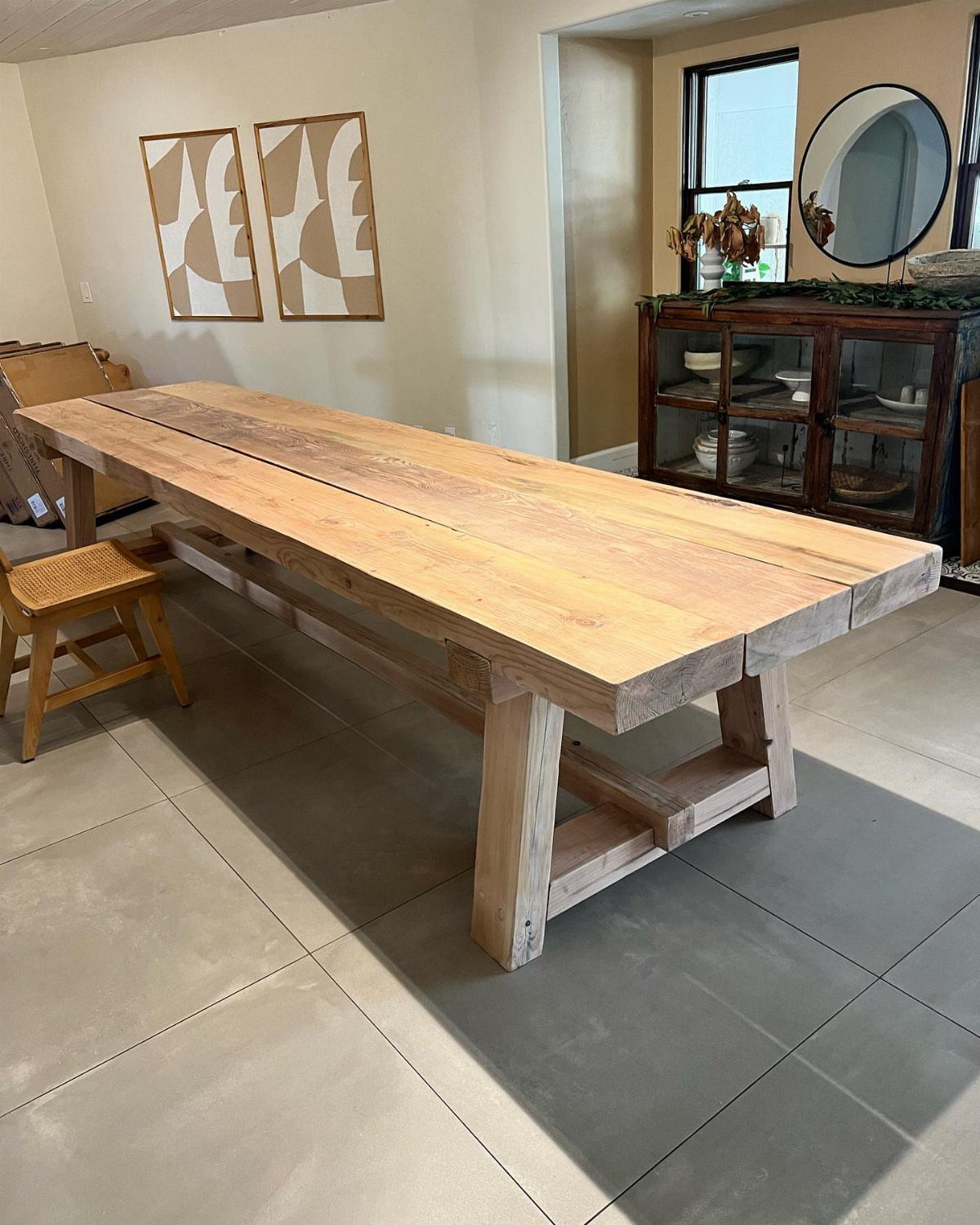 Furniture Plans Free for 16 Tables, Beds and Benches 1 Light wood farmhouse dining table with thick trestle legs on a grey tiled floor.