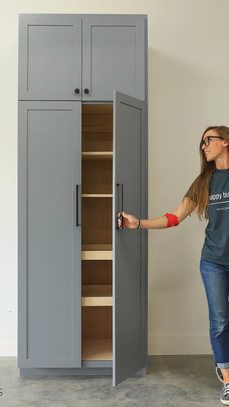 Furniture Plans Free for 16 Tables, Beds and Benches 10 Woman opening a tall grey wooden storage cabinet with interior shelving in a garage.
