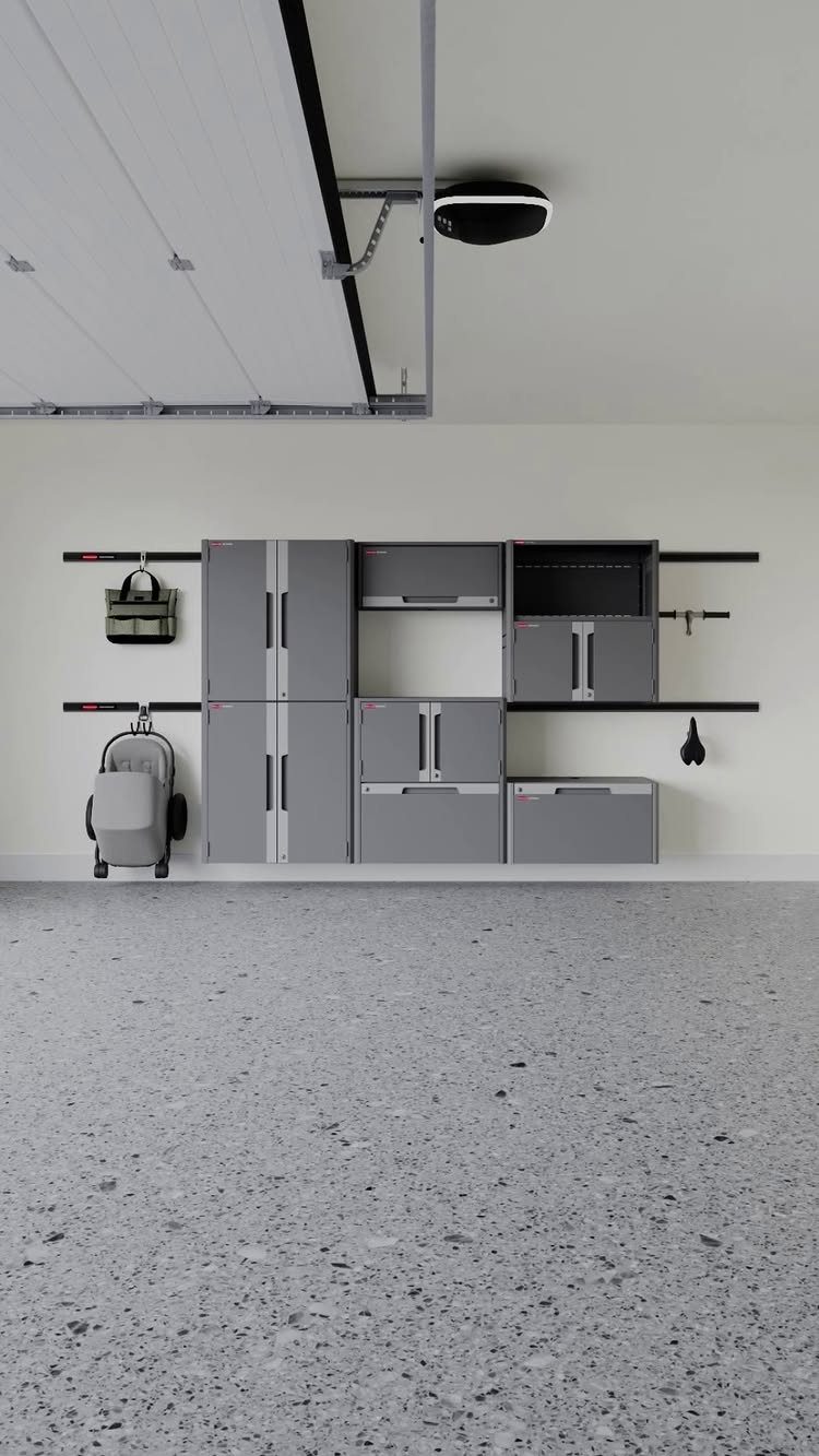 Grey modular metal cabinet system installed on a white garage wall with epoxy flooring.