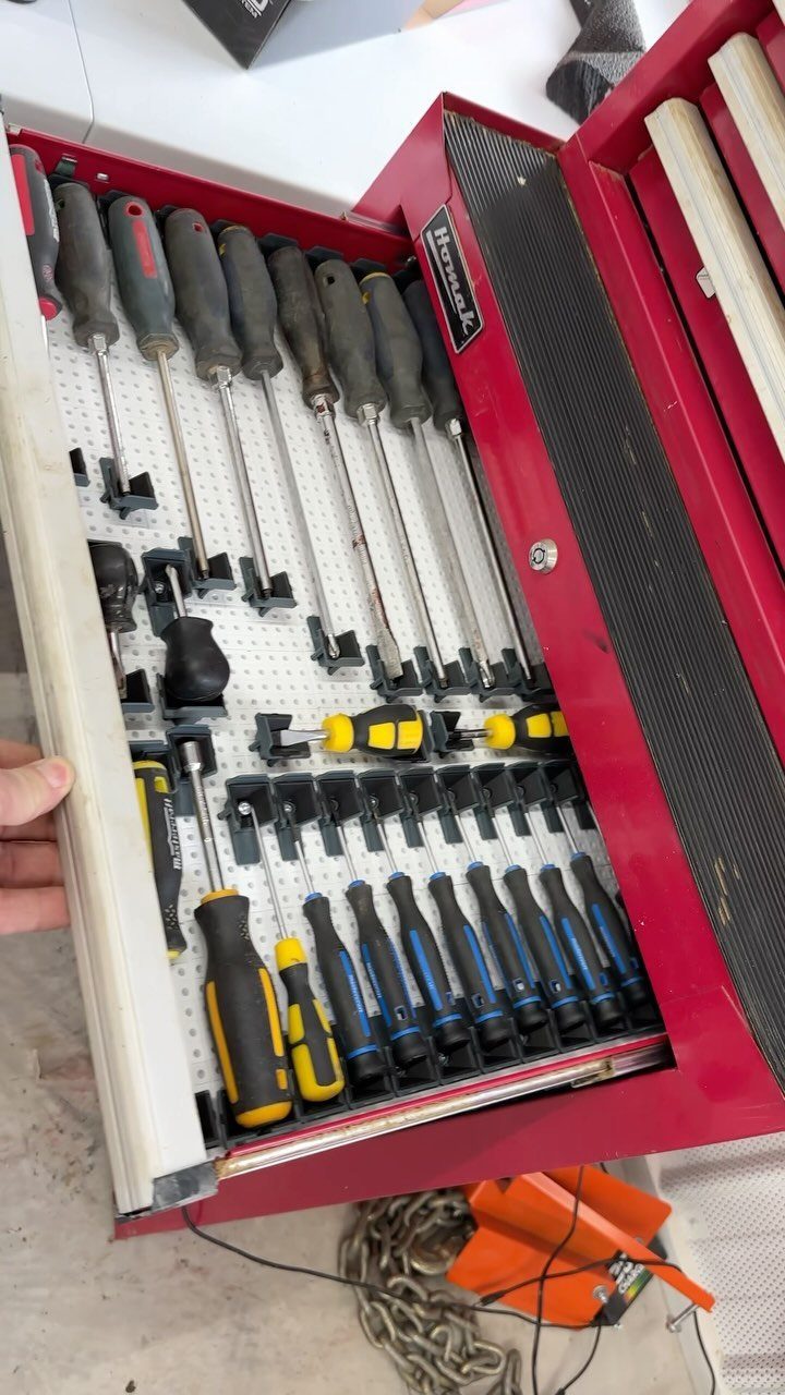 Red tool drawer with organized screwdrivers held in place by black plastic clips.