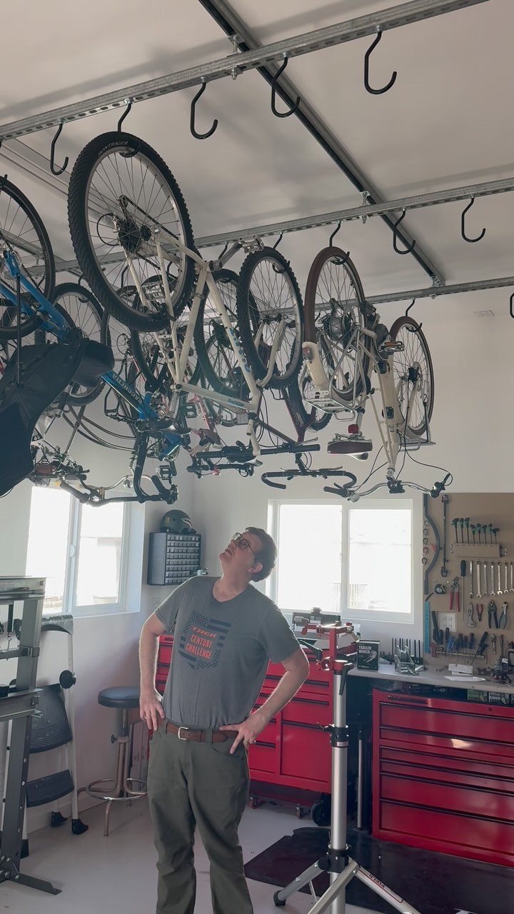 18 Garage Woodshop Ideas for Storage, Power, and Layout 3 Bicycles hanging from ceiling hooks in a garage with a man looking up.