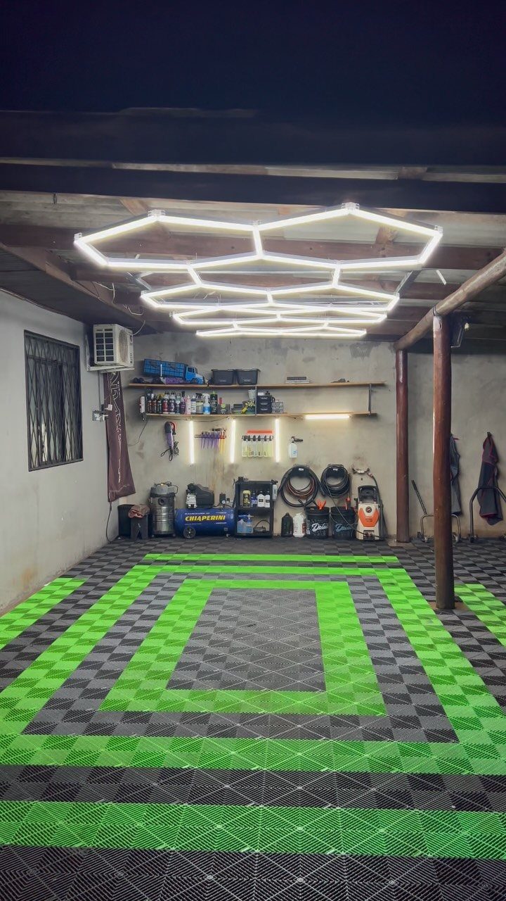 18 Garage Woodshop Ideas for Storage, Power, and Layout 7 Hexagonal LED ceiling lights illuminating a garage with green and black checkered flooring.