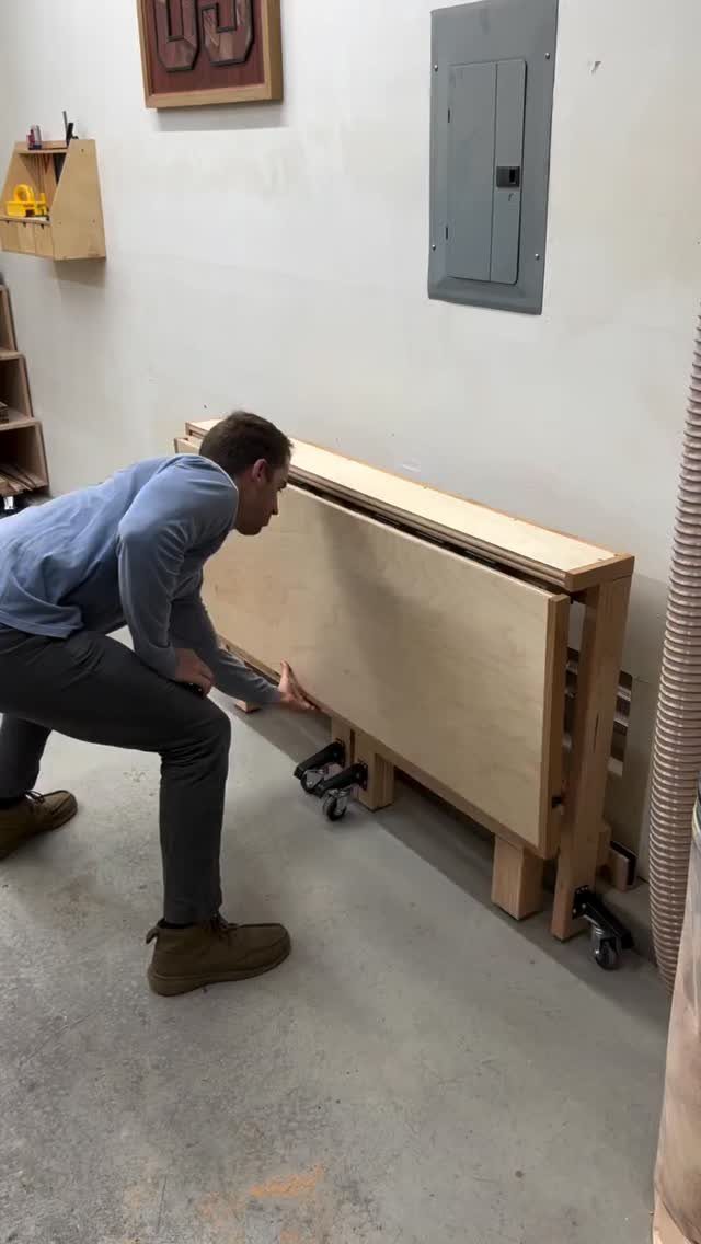 18 Garage Woodshop Ideas for Storage, Power, and Layout 8 Man crouching by a light wood mobile workbench on casters in a garage.