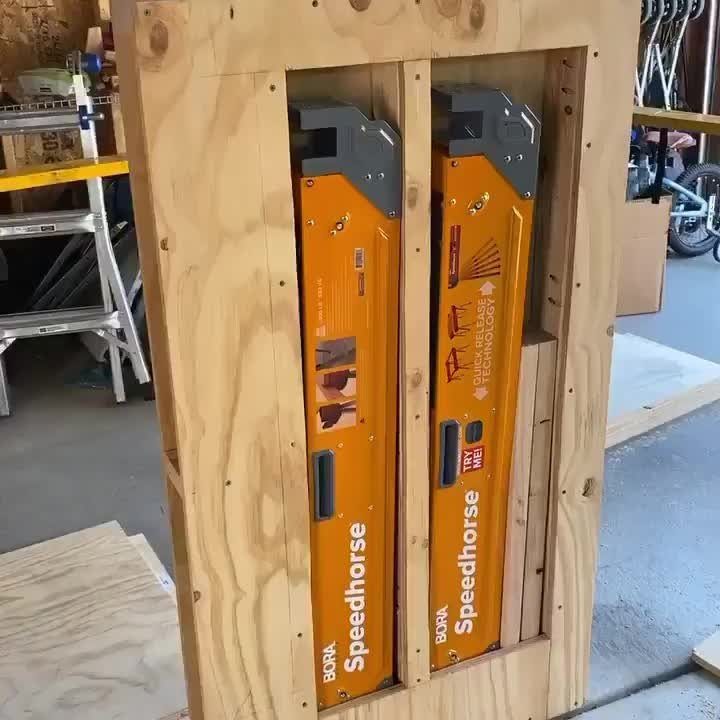 18 Garage Woodshop Ideas for Storage, Power, and Layout 17 Two orange folding sawhorses stored vertically inside a custom wooden storage frame.