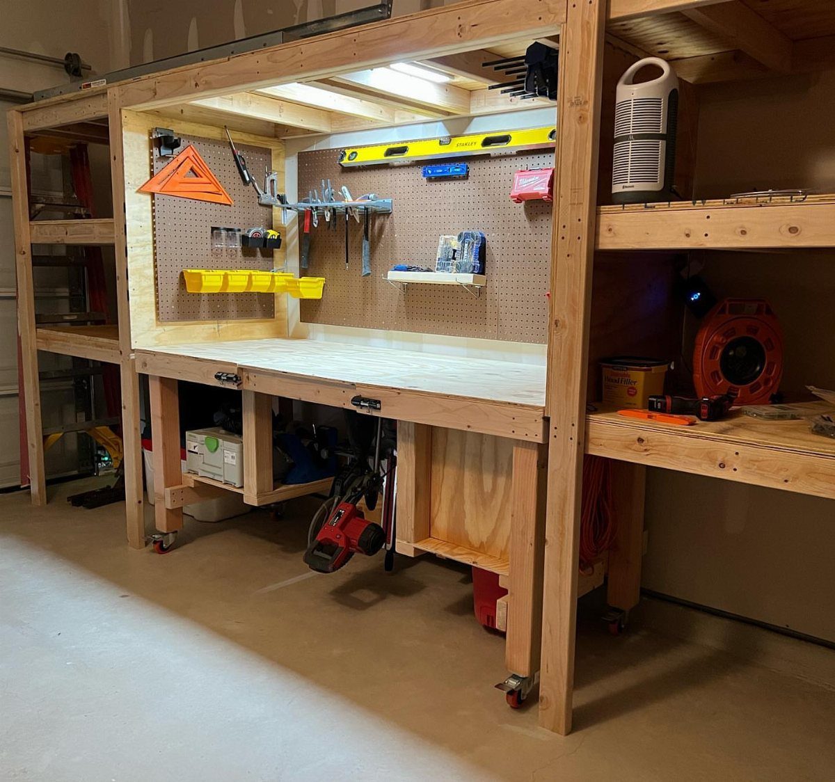 18 Garage Woodshop Ideas for Storage, Power, and Layout 13 Wooden workbench station with pegboard tool organization and LED lighting on wheels.