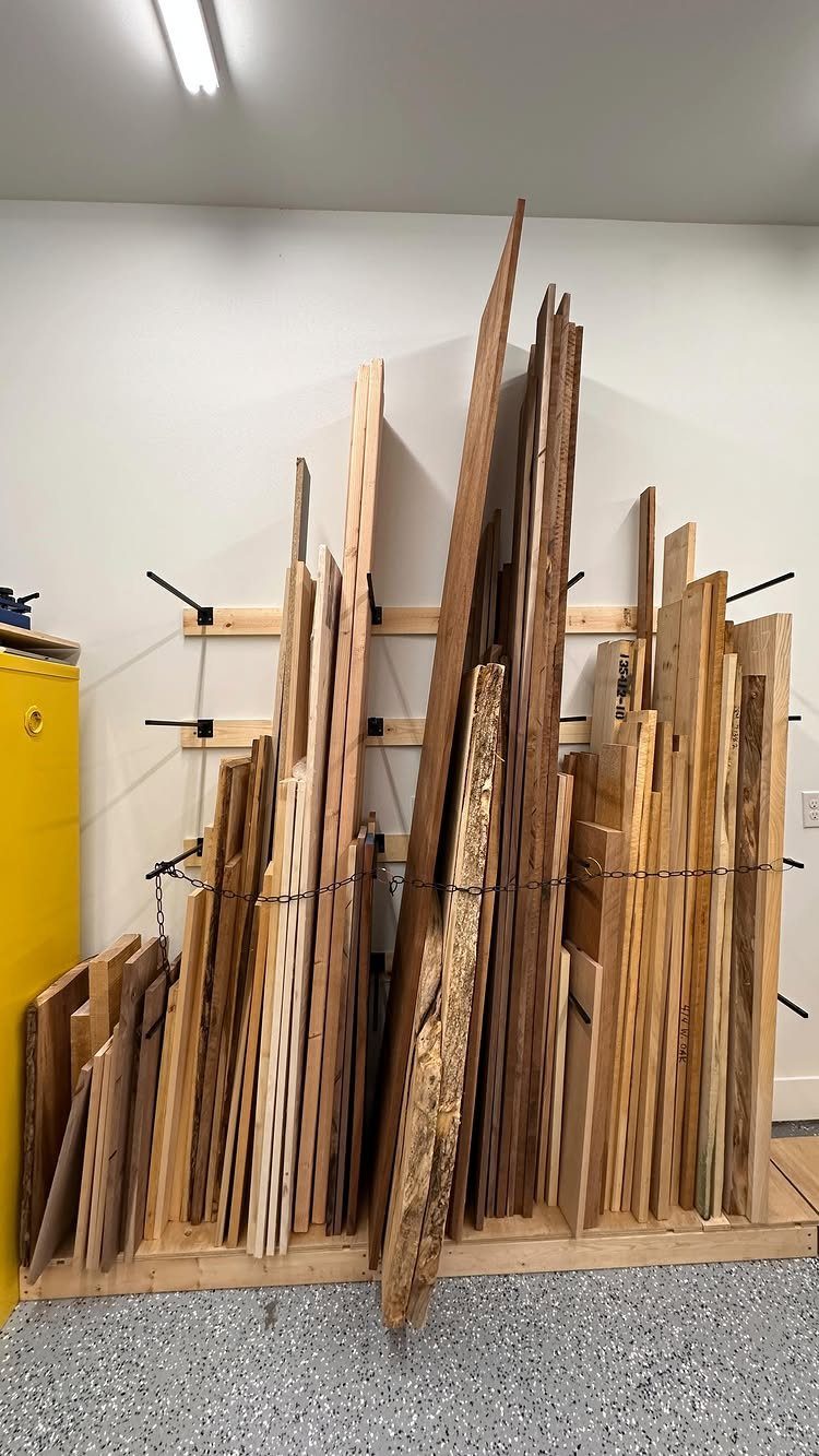 18 Garage Woodshop Ideas for Storage, Power, and Layout 16 Wooden boards stored vertically against a white wall with horizontal support rails.