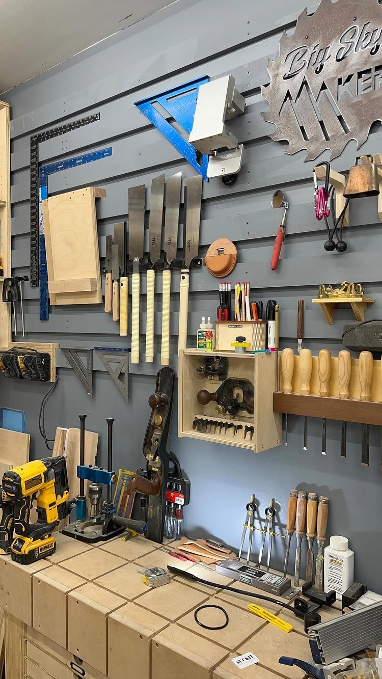 18 Garage Woodshop Ideas for Storage, Power, and Layout 1 Grey slatwall panels holding woodworking tools above a light wooden workbench.