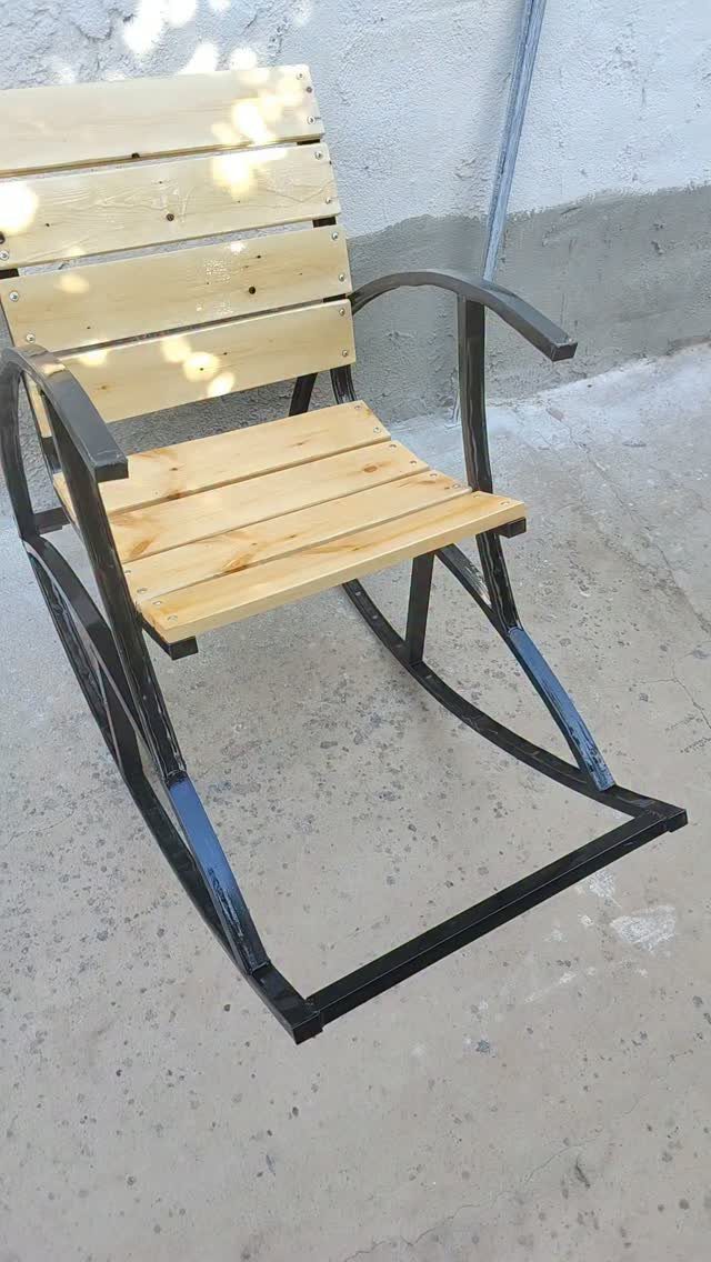 Homemade rocking chair with black metal frame and light wooden slats.