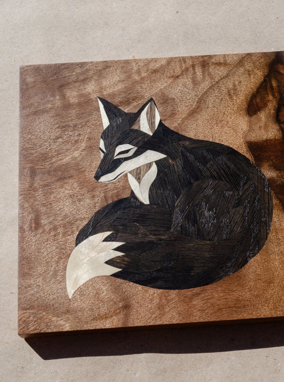 Inlays in Wood: 9 Ideas for Veneer, Resin and Metal 5 Curled-up fox created with dark and light wood inlays on a wooden board.