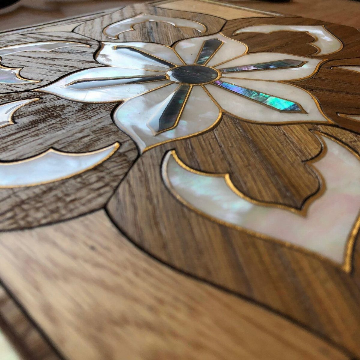 Inlays in Wood: 9 Ideas for Veneer, Resin and Metal 3 Floral inlay made of mother-of-pearl and gold wire embedded in dark brown wood.