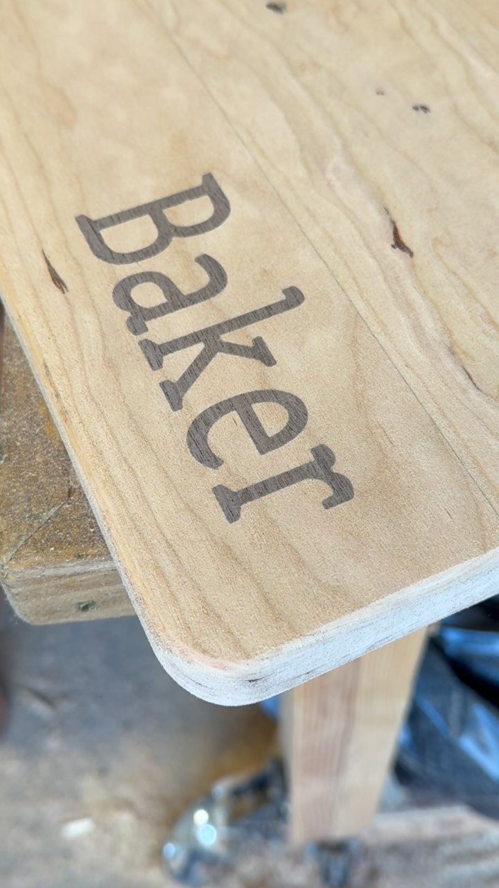 Inlays in Wood: 9 Ideas for Veneer, Resin and Metal 8 Wooden board with the word Baker inlaid in dark brown wood grain