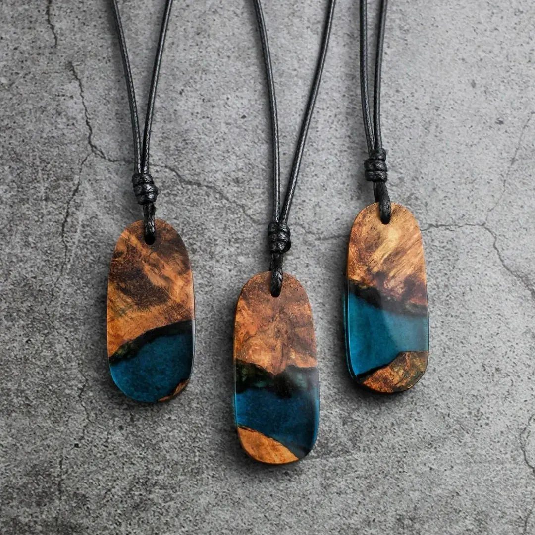Inlays in Wood: 9 Ideas for Veneer, Resin and Metal 2 Three wooden pendants with deep blue resin inlays on a grey stone background.