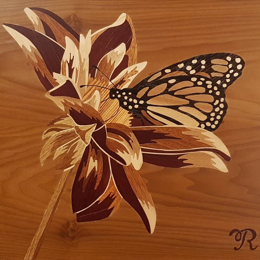 Inlays in Wood: 9 Ideas for Veneer, Resin and Metal 1 Monarch butterfly and flower created with intricate wood inlay on a wooden surface.