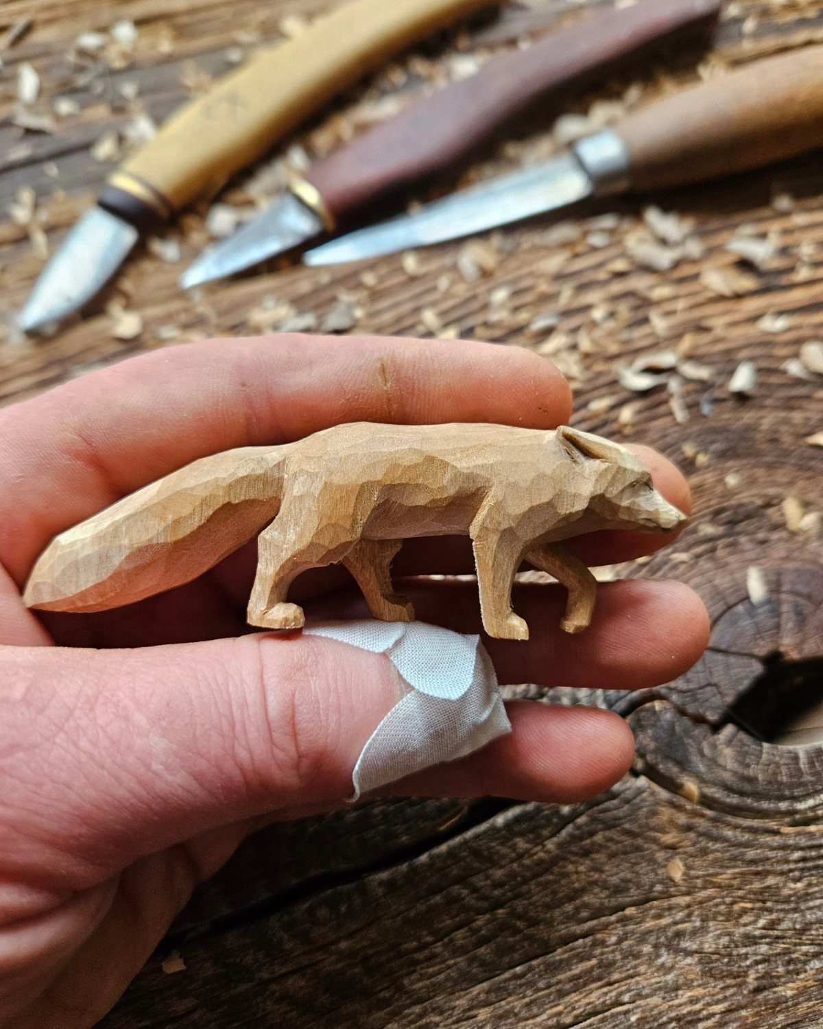 Intricate Wood Carving Ideas: 3 Styles to Try 3 Hand-carved wooden fox figure held above carving tools and wood shavings.