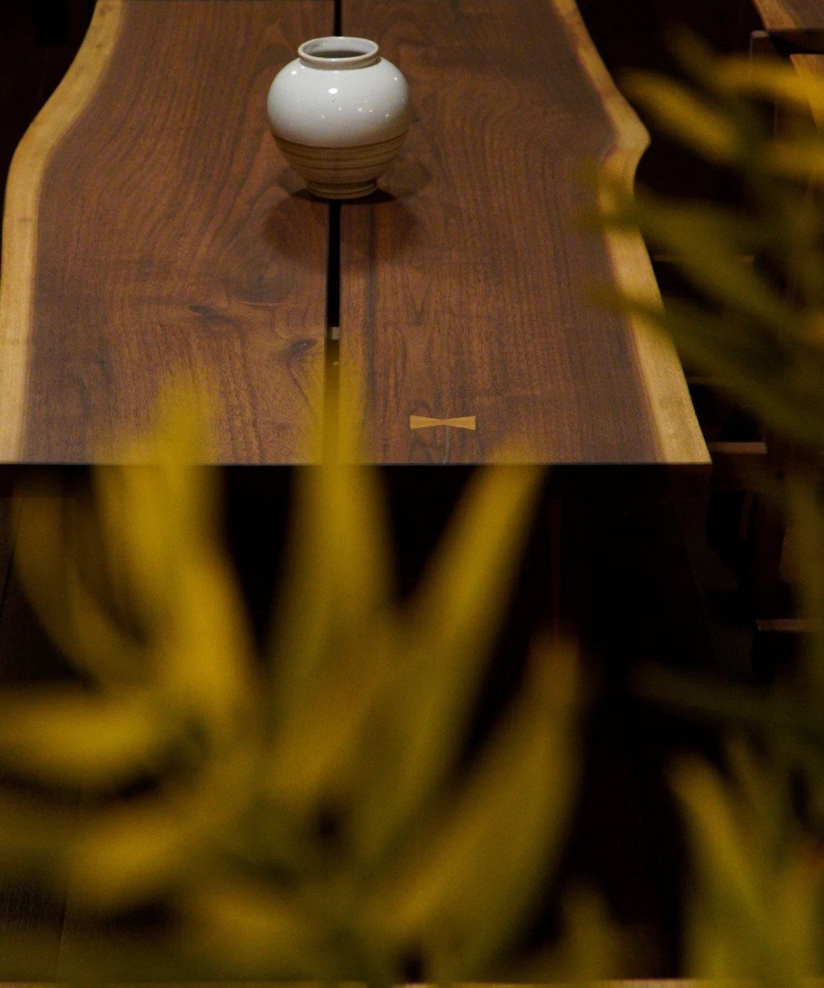 Live-edge wooden table with a butterfly joint and a white ceramic vase.