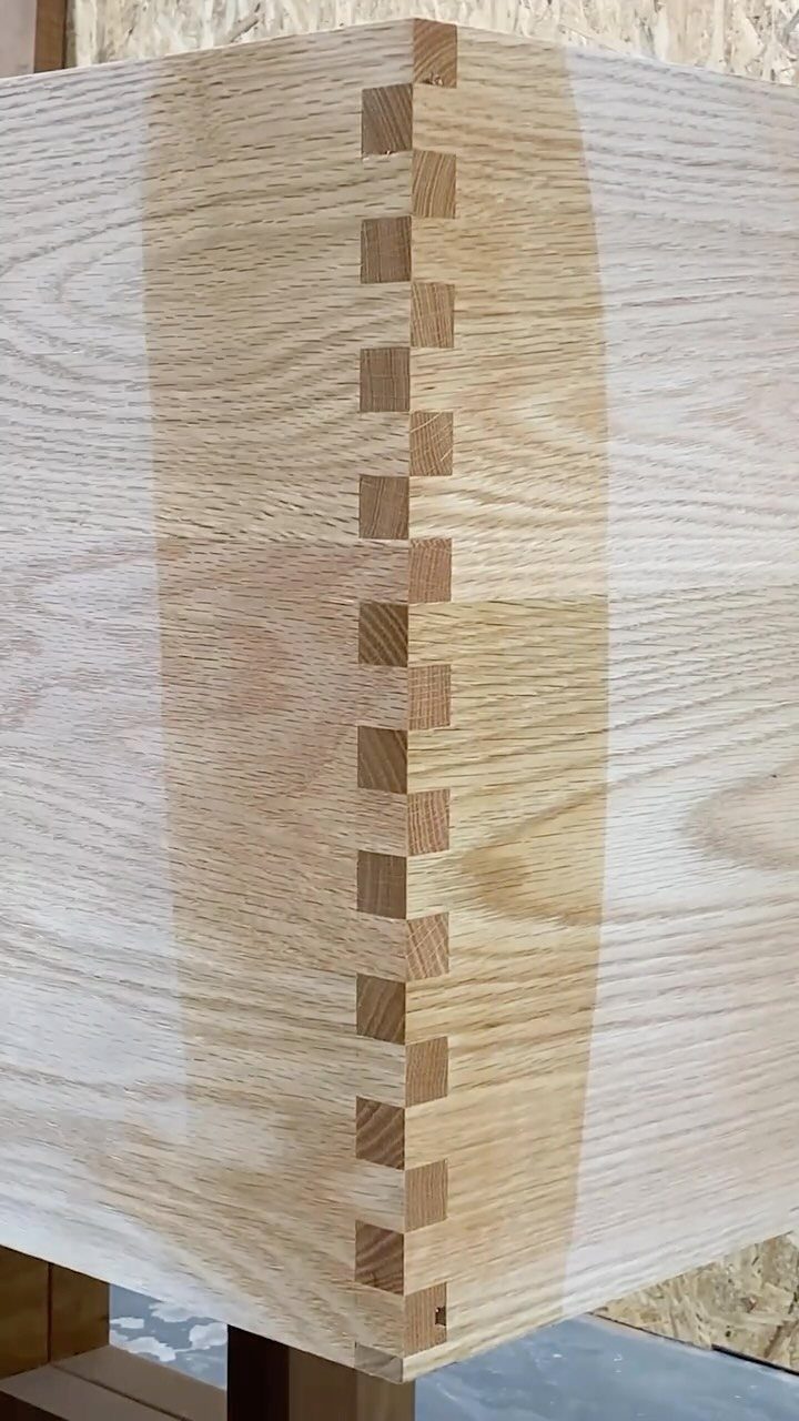 Interlocking box joint on the corner of a light-colored wooden box.