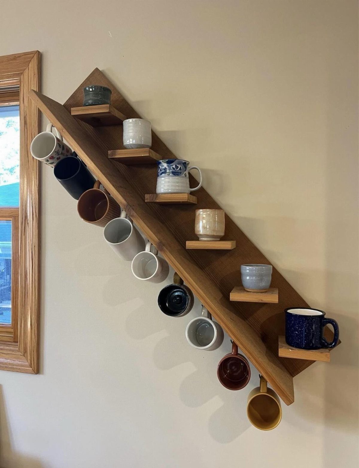 18 Kitchen Woodworking Projects for Storage and Gifts 3 Wooden wall-mounted mug rack holding various ceramic coffee mugs and cups.