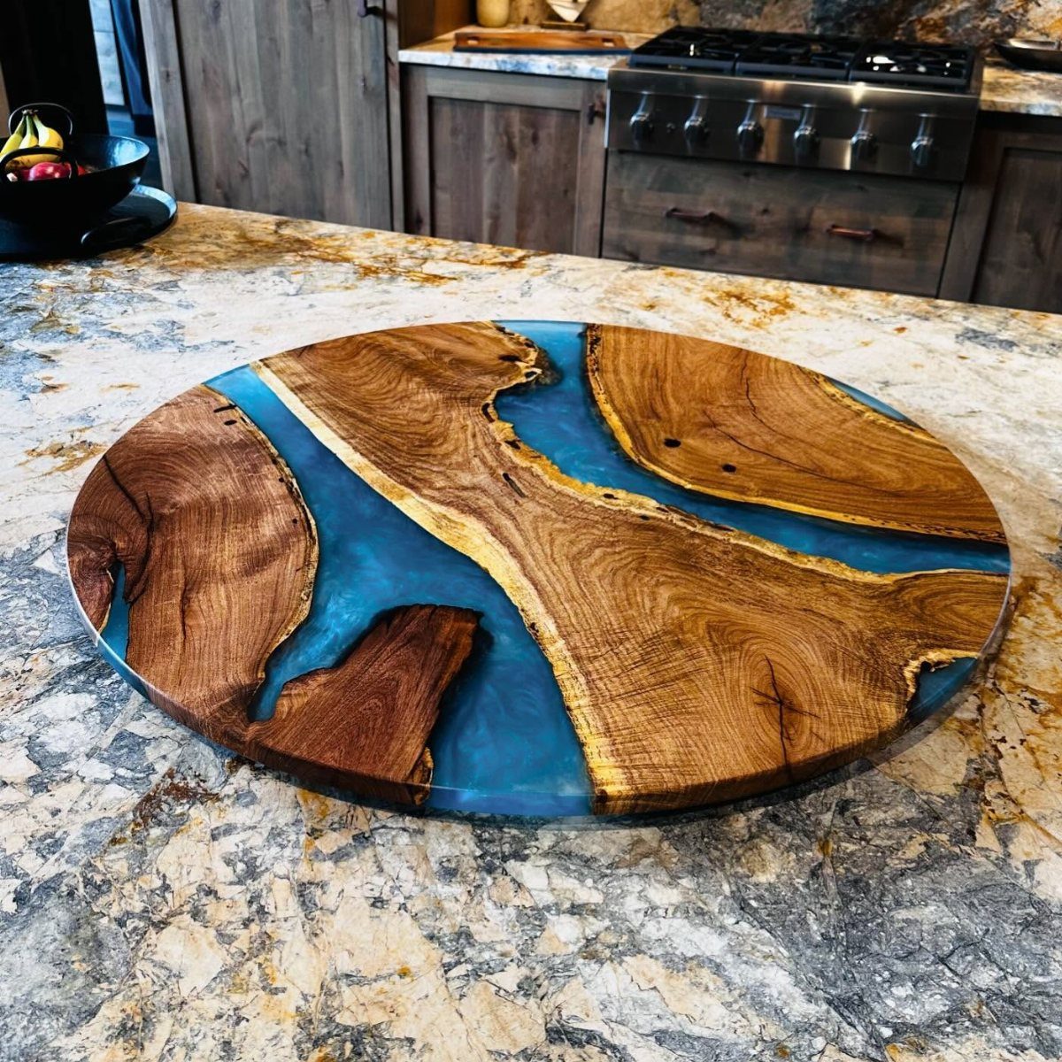 18 Kitchen Woodworking Projects for Storage and Gifts 15 Circular wooden cutting board with blue resin inlay on a granite kitchen counter