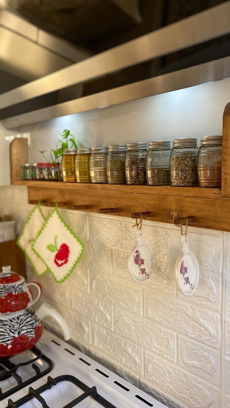 18 Kitchen Woodworking Projects for Storage and Gifts 18 Wooden wall-mounted spice rack with glass jars and hanging ladles in a kitchen.