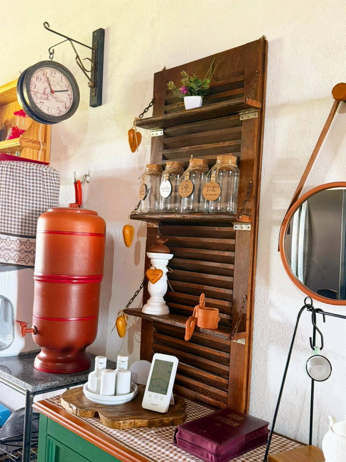 Rustic wooden shutter shelf with glass jars and a red vintage water boiler.