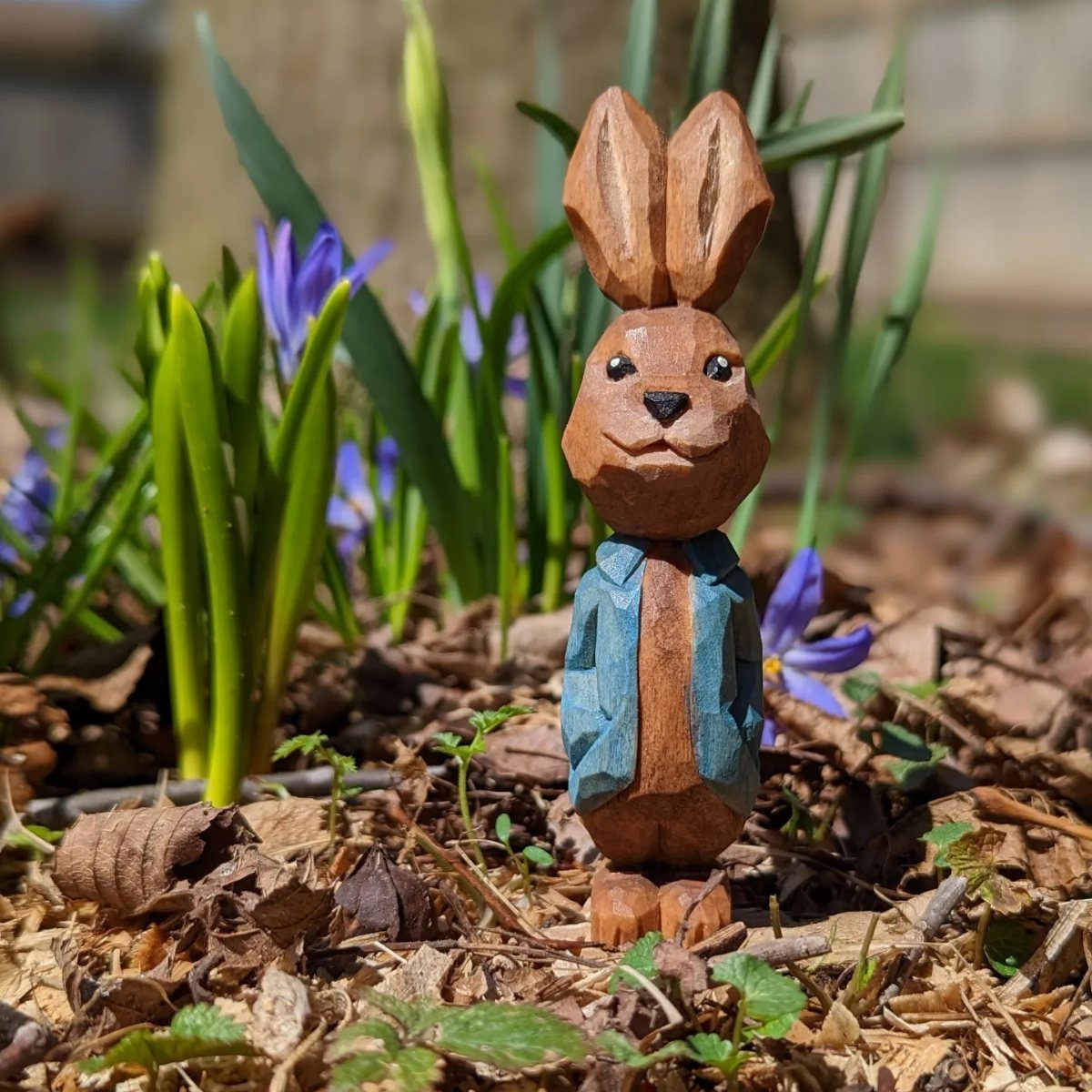 Lynn Doughty Carving: 4 Ideas for Busts and Projects 1 Hand-carved wooden rabbit wearing a blue jacket standing in a garden with purple flowers