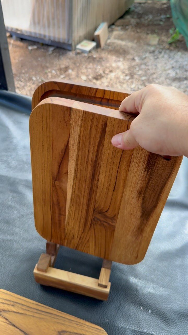 32 Mini Wood Projects for Beginners and Scrap Wood 9 Wooden cutting board resting in a small wooden stand held by a hand.